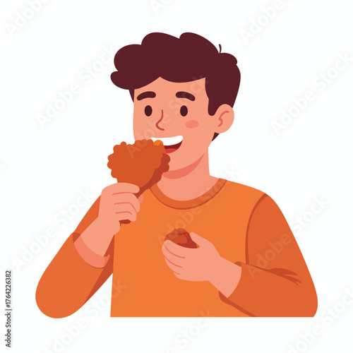 A smiling young man happily eating a piece of fried chicken.