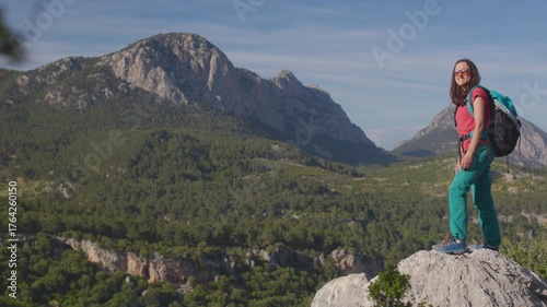 A girl stands on a mountaintop with a feeling of joy, satisfaction, and victory. A girl at the top of a mountain celebrates reaching the summit. Concept of achieving success. A happy life.
