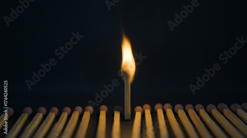 Dramatic close up of a single burning match igniting against a dark background with used matches