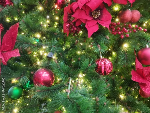 Bright Christmas tree decorated with red flowers ornaments and warm golden fairy lights