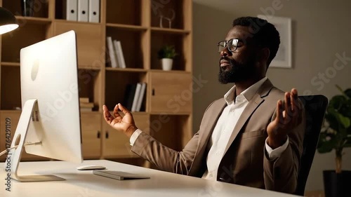 Focused Businessman Meditating at Desk with Computer for Mindfulness and Stress Relief in Office During Work Break Posing with Eye Glasses and Light Brown Suit Indoor