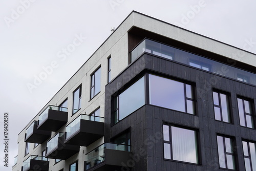 Modern apartment building with balconies and large windows under a cloudy sky in an urban setting