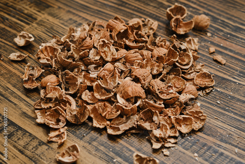 Pile of brown nutshells scattered on wooden surface during snack time at home