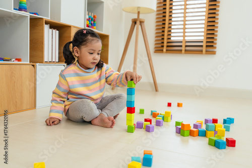 toddler girl playing block toy to stacks building cubes at home
