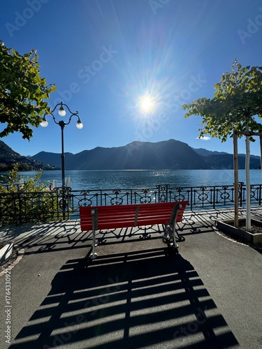 Red bench by lake Lugano on a sunny day 