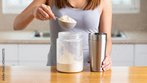 Woman preparing protein shake at home by adding protein powder into blender with milk, healthy nutrition and fitness lifestyle concept. Protein RTD, functional beverage, wellness drink, protein shake