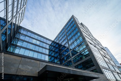 Glass high office building as headquarters of several companies and workplace for many people. Modern architecture in the city center in a business park. Detail of glass windows and reflection of clou