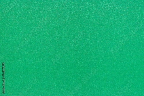 A detailed, full-frame texture of the synthetic green surface of a badminton court, providing an excellent abstract background showcasing the material's granular structure.