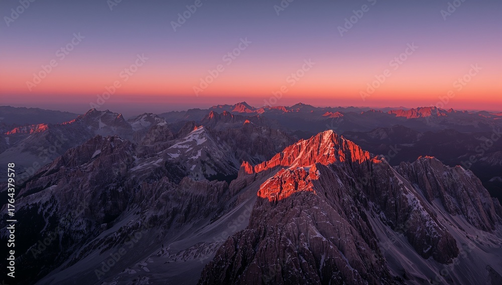 Naklejka premium Bathing jagged mountain peak in pink-red alpenglow at dawn, with snow patches and ridges