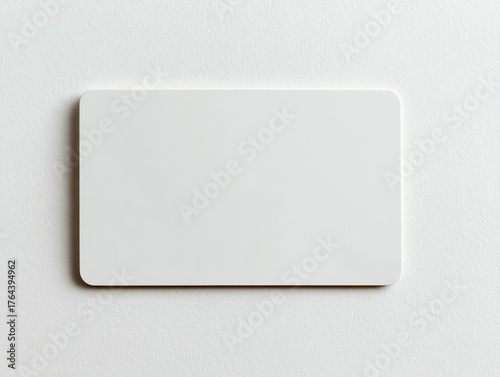 Blank white plastic card against white surface, rounded edges, minimalist, clean, bright, simple object