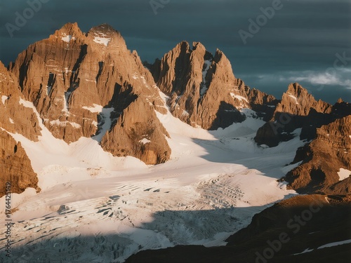 Rugged mountain peaks with snow-covered glaciers under dramatic lighting