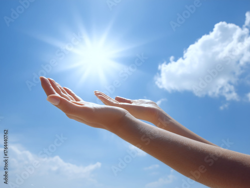 青空に向かって手を差し伸べる女性の手元と太陽の光希望や解放感を表現する明るいイメージ