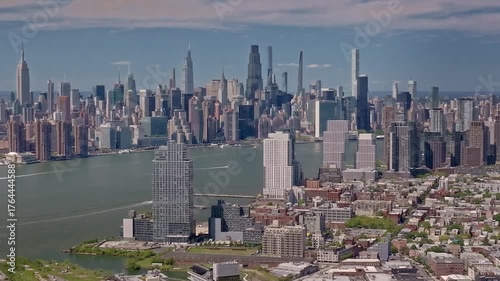 A slowly rotating, cinematic drone shot capturing the iconic New York City skyline as seen from Brooklyn across the East River, showcasing breathtaking scenery of the dynamic Manhattan cityscape.