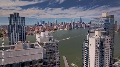 A cinematic drone shot rotating and rising above modern Brooklyn high-rise apartment buildings, revealing the Manhattan skyline and the iconic Empire State Building in the distance, of New York City.
