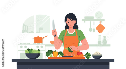 Young woman in an apron chopping fresh vegetables in the kitchen.