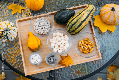 Schilderij op canvas Outdoor flatlay of fall gourds and various supplements in glass bowls arranged on a wooden tray over autumn leaves