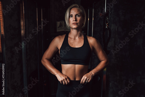 Caucasian fitness woman looking at camera in a gym, showcasing dedication and strength