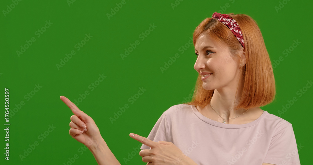 Obraz premium Woman points at commercial promotion or advertising copy space or marketing mockup. Portrait, product placement girl and female chroma key model on mock up background