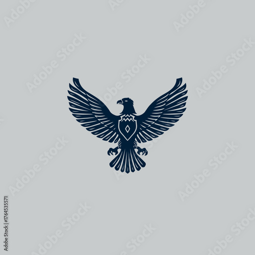 Majestic dark blue flying eagle emblem with outstretched wings and a decorative shield on its chest. Powerful bird of prey symbol on gray.
