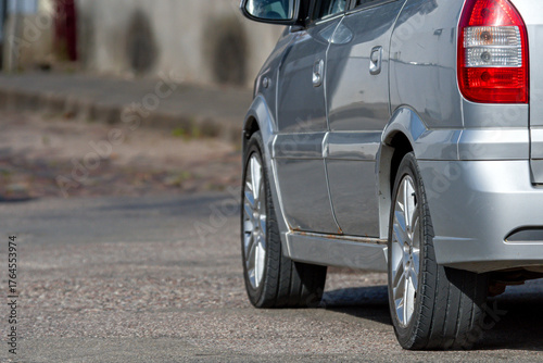 Silver car parked on a quiet street with paved surface and curbside