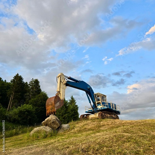 Blue excavator on construction site at sunset