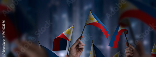 Philippines flags in their hands on a blurred urban background