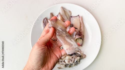 Fotografia A hand tenderly presents glistening squid, a delicacy for Lunar New Year feasts