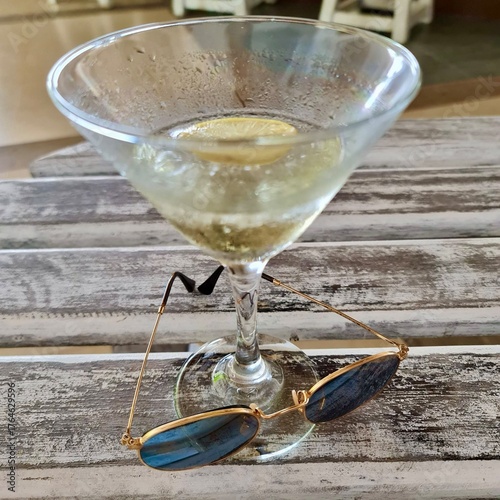 Refreshing cocktail with lemon and sunglasses on wooden table