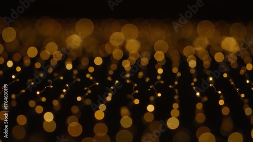 Glowing golden bokeh lights on dark background. Artistic abstract with blurred round lights