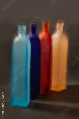  Four vintage bud vases of frosted glass of different colors with effects blurs in motion on dark background