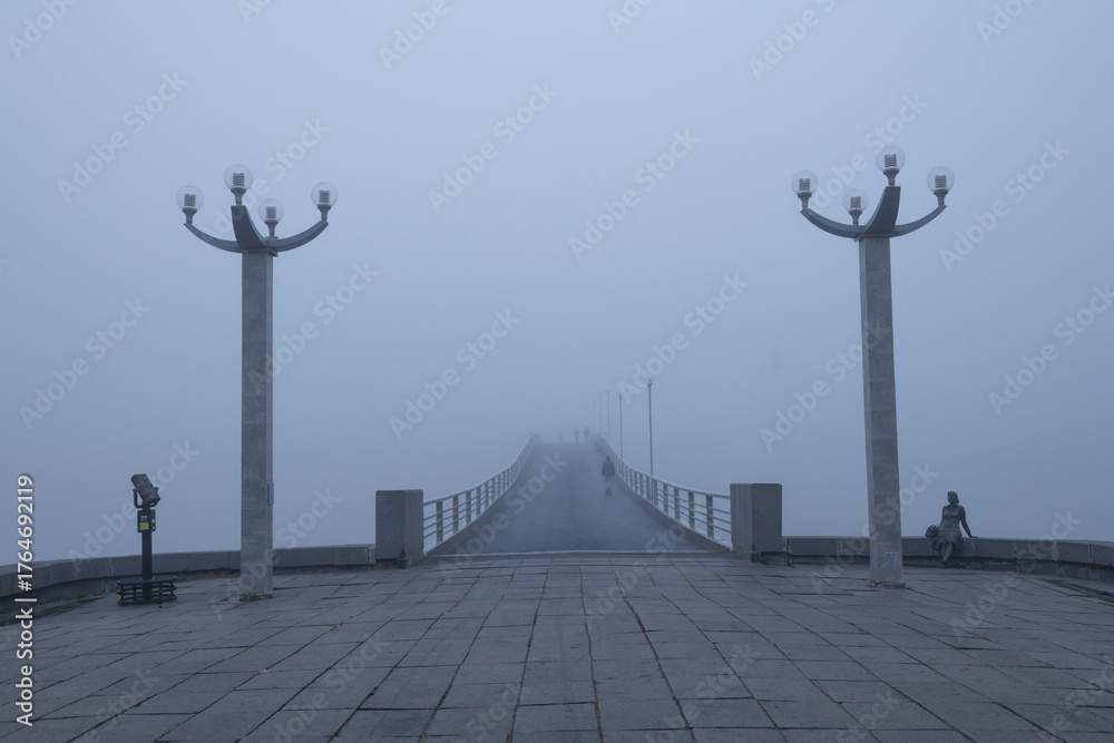 Naklejka premium At the pedestrian (Humpback) bridge over the Volkhov River in the early foggy morning. Veliky Novgorod, Russia