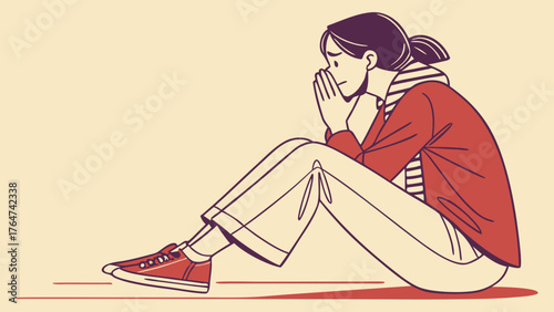 A young woman sits with her knees pulled to her chest, looking distressed and covering her mouth with her hands.