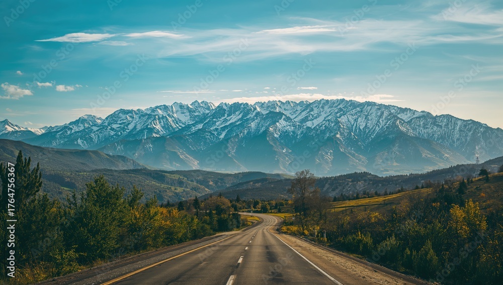 Fototapeta premium Beautiful highway leading to snowy peaks under a bright blue sky