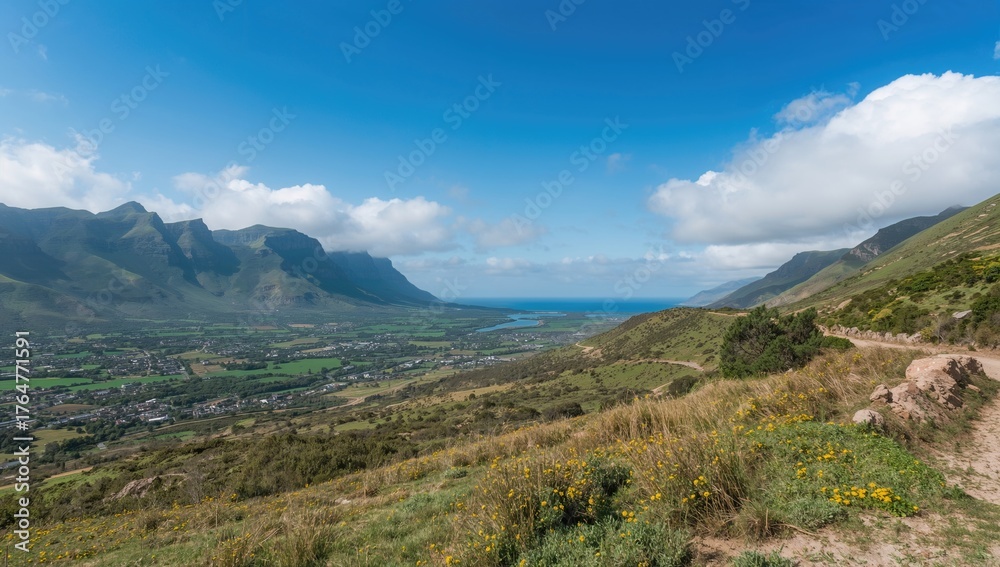 Fototapeta premium Mountain pass with river and expansive coastal plain in the background, featuring sky, landscape, road, mountains, greenery, blue hues, agriculture, and wheat fields