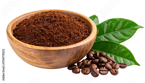 Close-up of a wooden bowl filled with ground coffee, beside coffee beans and green leaves on a black background