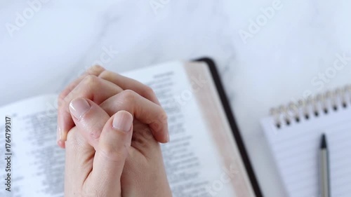 Hands praying on top of open holy bible. Top view. Christian thanksgiving, forgiveness, and faith in God Jesus Christ, biblical concept.
