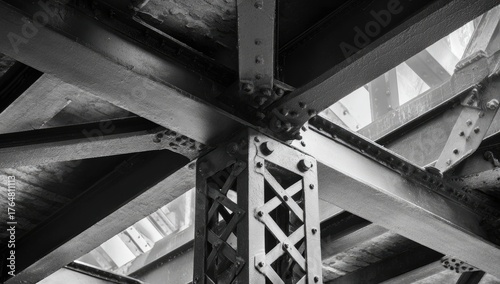Black & white image of a network of metal beams joined with rivets, forming a structural support