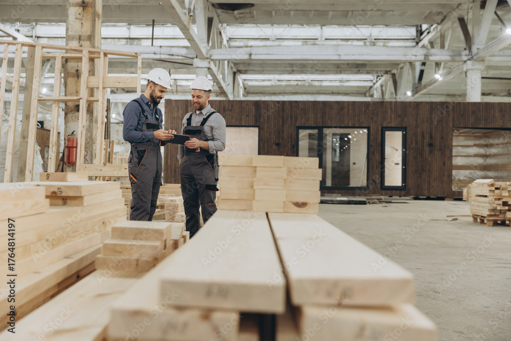 Fototapeta premium Construction workers using tablet and inspecting wooden planks in factory