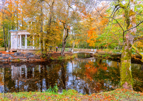 Late autumn in old public park, walking bridge and abandoned resting pergola