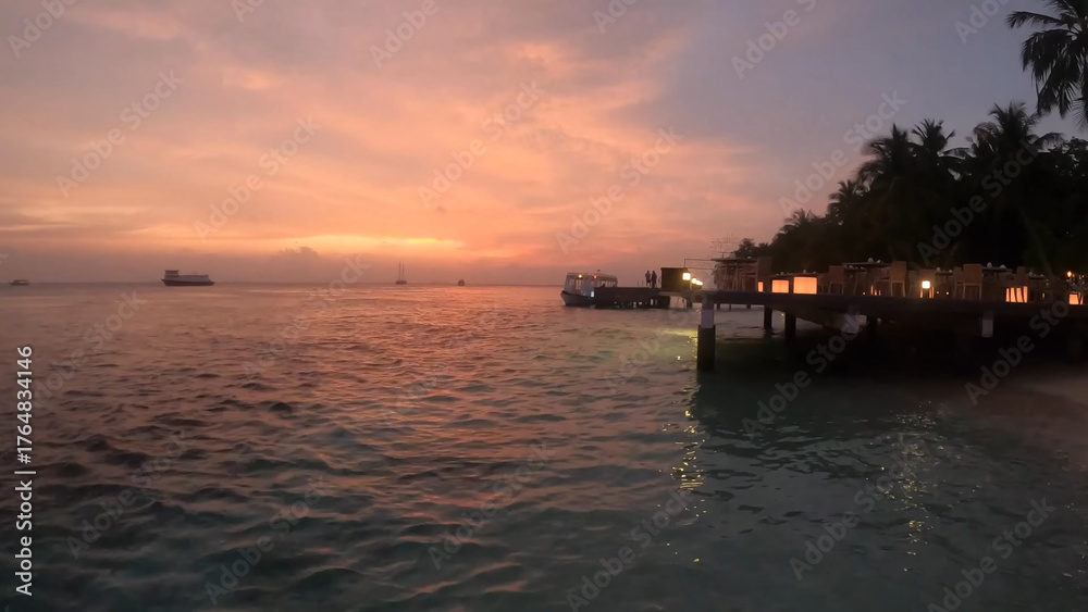 Naklejka premium Luxury resort photo of Maldives tropical paradise islands in Indian Ocean at sunset with hotel territory, palm trees. Beautiful evening photography, sky with clouds. 