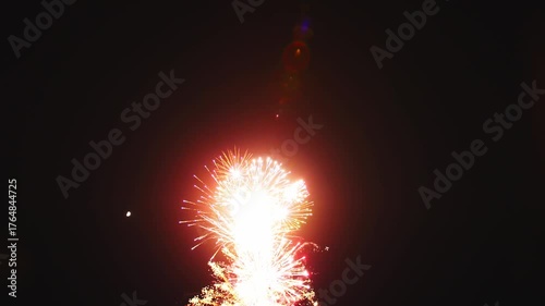 Bright fireworks illuminate the dark night sky, creating a stunning display of colors and patterns. The event captures the excitement of a local celebration, drawing a large crowd.