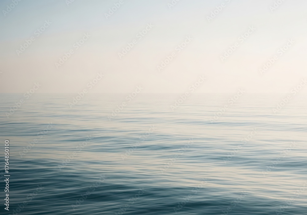 Obraz premium Calm sea under a hazy sky, with gentle ripples on the waters surface creating subtle patterns and a serene, tranquil atmosphere