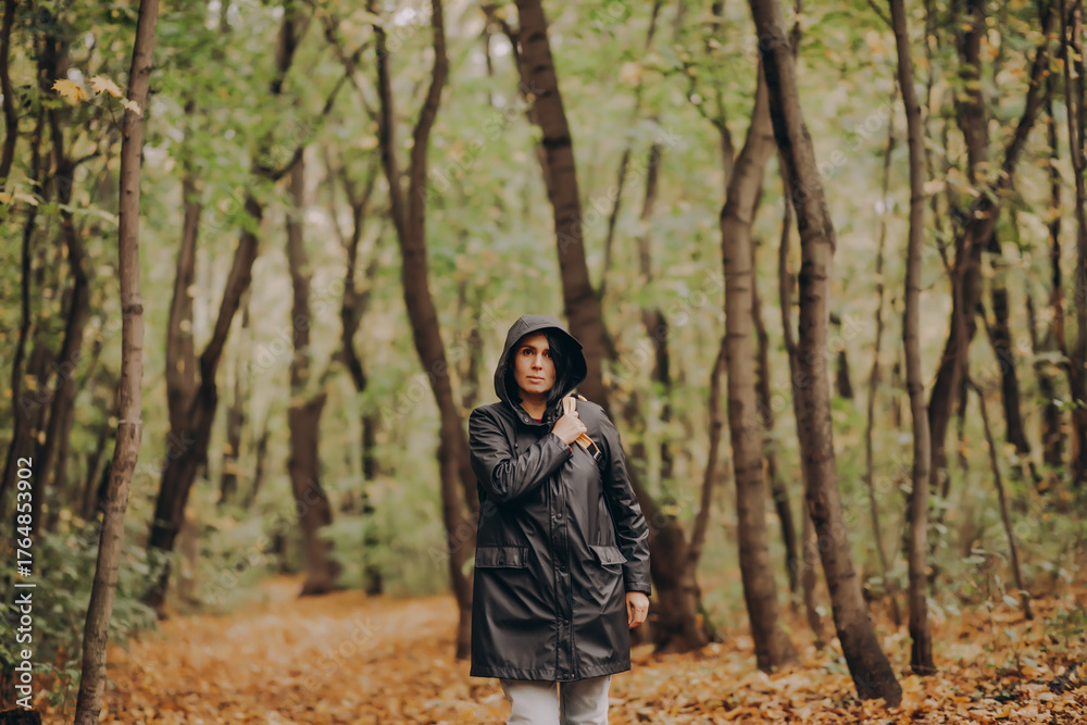 Naklejka premium Woman with backpack hiking on footpath in autumn forest and relaxing outdoor.