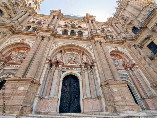 Magnificent frontage of the Catholic Malaga Cathedral (Basilica de la Encarnación). 18th-century portals in Baroque style with a central intricately carved medallion. Aug 4, 2025, Malaga, Spain.