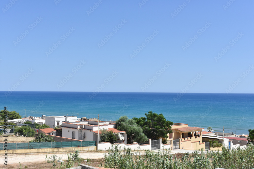 Fototapeta premium Sea view from the window. Triscina, Sicily, Italy. The Mediterranean Sea. Vacation in Sicily. Travel to Italy. Summer and Holidays. Summer villas. Sicilian village near Trapani. Relax. 