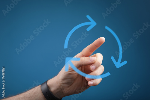 A hand pointing towards a circular arrow, suggesting concepts of process, cycle, and repetition on a blue background. Ideal for business, techno