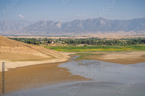 Scenic rural landscape view of Turkestan mountain range with water reservoir in foreground, Istaravshan, Sughd, Tajikistan