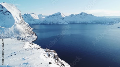 Excited hiker stands on the edge of a cliff on Kvaloya Island in Northern Norway