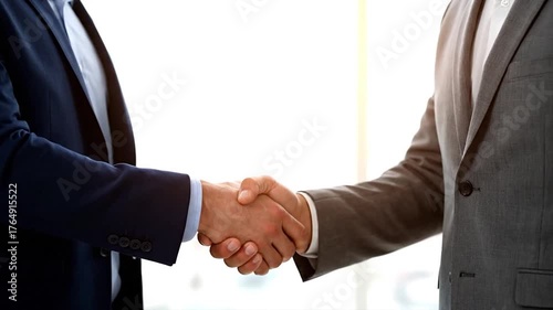 Two people in suits shake hands, a symbol of agreement. Close-up on the clasp