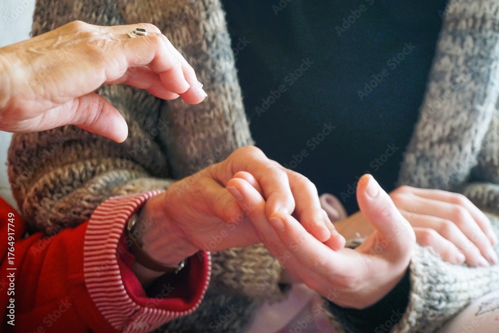 Fototapeta premium Handmassage zwischen alter Großmutter und jugendlicher Enkeltochter auf Sofa zuhause